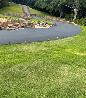 Sweeping sealed driveway curving past a stone retaining wall